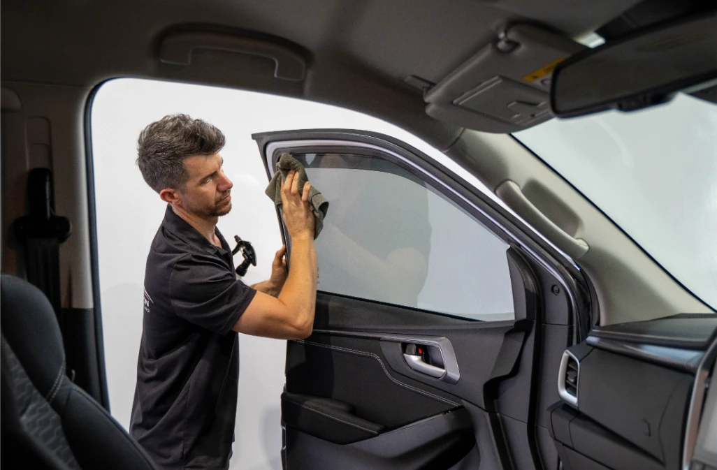 Auto Affection Detailing technician cleaning a car window during a maintenance detail